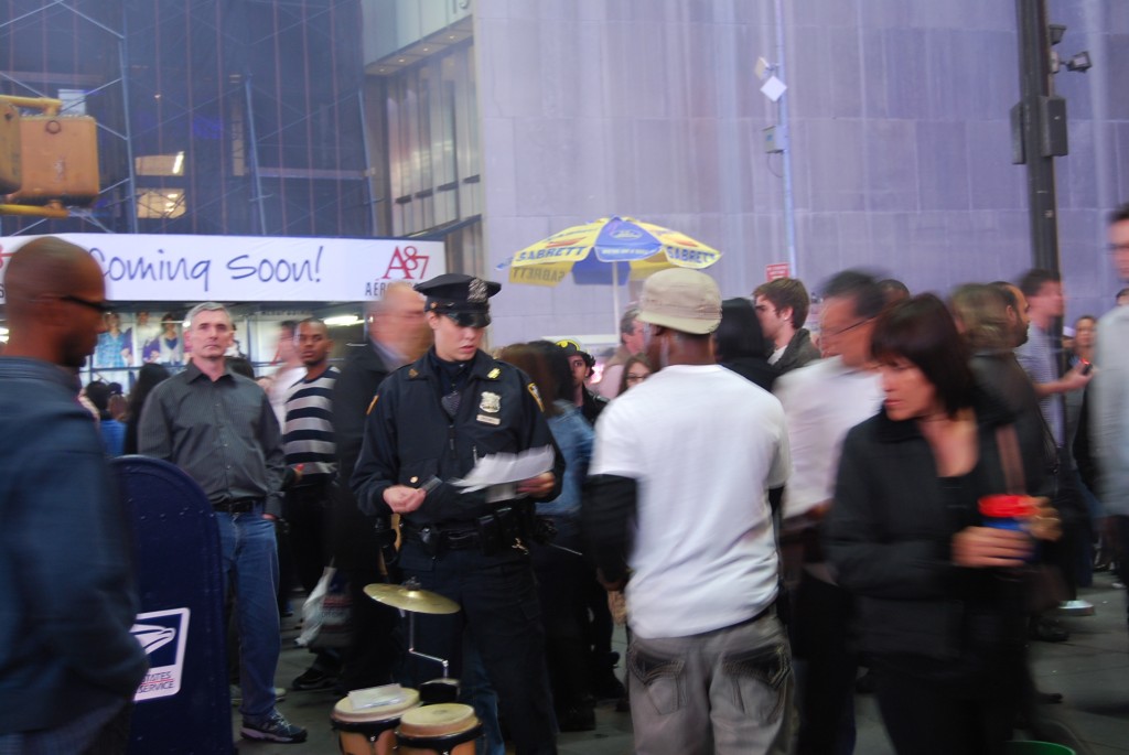 девушка - полицейский проверяет документы у уличных музыкантов на Тайм Сквер 8 Октябрья 2010